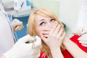 Terrified woman with dental phobia, scared at dentist visit.