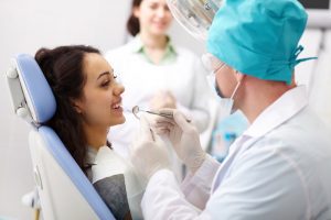 Young female patient receiving dental care from a friendly doctor and his assistant